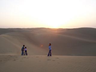 Des enfants jouent dans le désert au couché du soleil