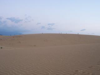 Des dizaines de gens au loin sur les dunes repartent chez eux